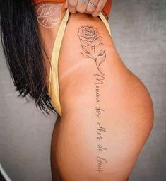 a woman with a tattoo on her back showing the word love and a rose behind it