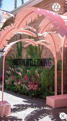 an outdoor area with pink furniture and flowers in front of a building that says pretty little thing