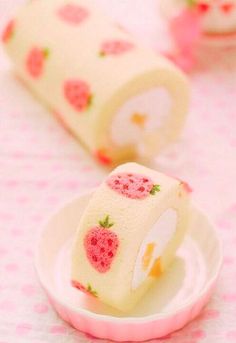 two rolls of cake with strawberries on them are sitting on a pink and white plate