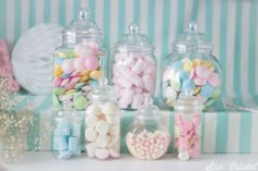 several glass jars filled with candy and marshmallows