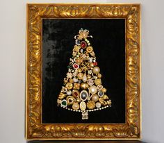 a gold framed christmas tree with jewels and pearls on it's bottom is hanging on the wall