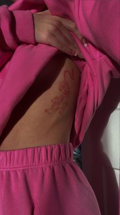 a woman with a tattoo on her stomach wearing pink sweatpants and a matching ring