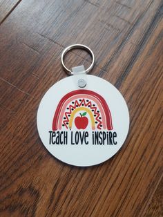 a keychain that says teach love inspire with an apple and rainbow on it