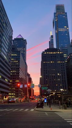 an empty city street at dusk with tall buildings in the background and traffic lights on both sides