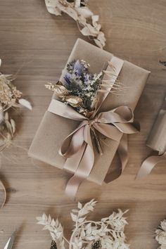 two wrapped presents with ribbons and flowers on top of a wooden table next to scissors