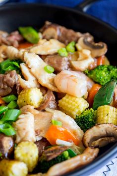 a skillet filled with shrimp, broccoli and carrots on top of a blue towel