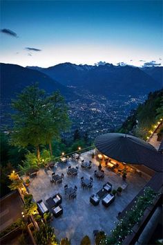 an aerial view of a restaurant with mountains in the background at night, overlooking city lights