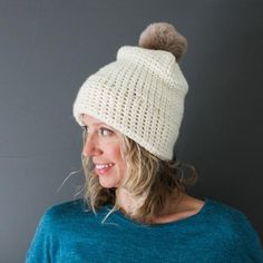 a woman wearing a white knitted hat with a pom - pom