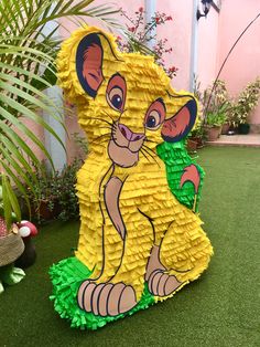 the lion king pinata is sitting in the grass next to a potted plant