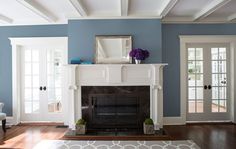 a living room with blue walls and white trim on the fireplace mantel, along with hardwood flooring