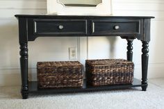 a black table with two baskets under it and a mirror on the wall behind it