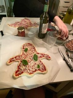 a person sitting at a table with some pizzas and other food items on it