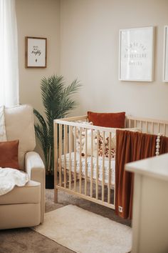 a baby's room with a crib, chair and potted palm tree