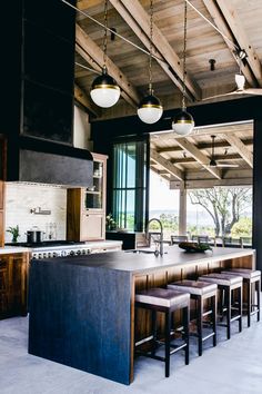 an open kitchen and dining area with stools in front of the island countertop