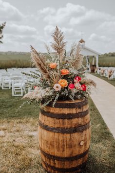 a wooden barrel with flowers and greenery on the side for an outdoor wedding ceremony