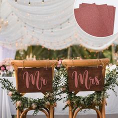 two wooden chairs with red mr and mrs signs on them sitting in front of a white tent