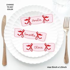 a white plate with red bows and name tags on it, next to silverware