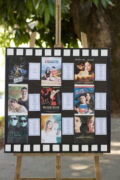 an easel with pictures on it in front of a tree and some trees behind it