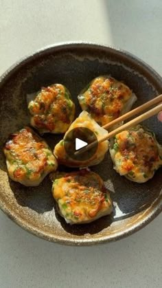 a person holding chopsticks over some food in a bowl