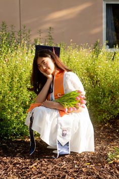 a woman sitting on the ground with flowers in her hand