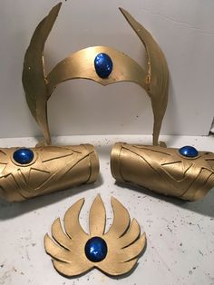 three pieces of art made out of gold and blue material on top of a table