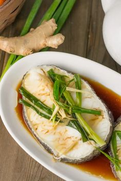 an image of steamed fish in sauce on a plate with green onions and celery