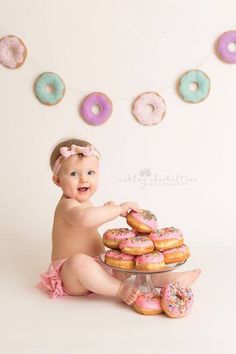 a baby sitting on the floor with donuts in front of her