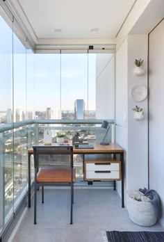 a balcony with a desk and chair next to a large glass window overlooking the city