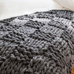 a large gray blanket sitting on top of a bed