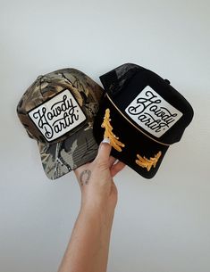 Customizable high crown, foam or structured, adjustable snap back trucker hat detailed with our best selling "Howdy Darlin'" design on an ivory and black embroidered patch. One size fits most. Hats shown in listing image: (Top) Camo - 1 hat (Bottom) Black/gold hat Adjustable Trucker Hat With Embroidered Logo And Flat Brim, Trucker Snapback Hat With Patches And Curved Bill, Adjustable Snapback Trucker Hat With Embroidered Logo, Adjustable Trucker Hat With Embroidered Logo, Trucker Hat With Embroidered Logo And 5-panel Design, Adjustable Trucker Baseball Cap With Letter Patch, Snapback Trucker Hat With Logo Patch, Embroidered Logo Trucker Hat With Flat Bill, Adjustable Snapback Trucker Hat With Logo Patch