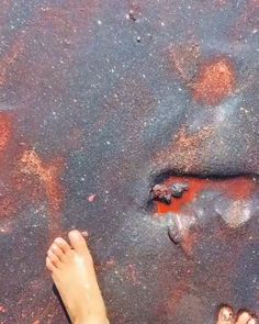 two people standing in the sand with their feet up and one person's foot sticking out