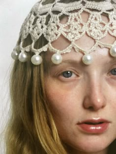 a woman wearing a crocheted head piece with pearls