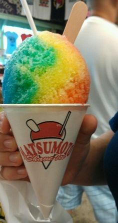 a person holding an ice cream cone with rainbow topping