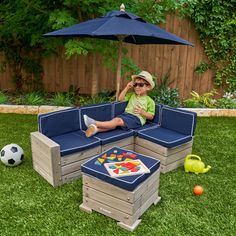 a young boy sitting on top of a blue couch next to a soccer ball and an umbrella