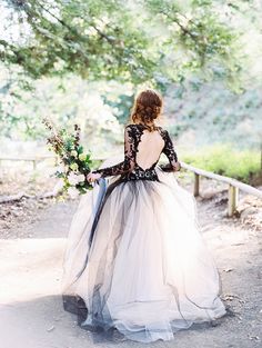 a woman in a long dress walking down a path with flowers on her shoulder and back