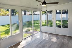 an empty room with sliding glass doors and a ceiling fan in the middle of it