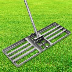 a large metal rake laying on top of green grass