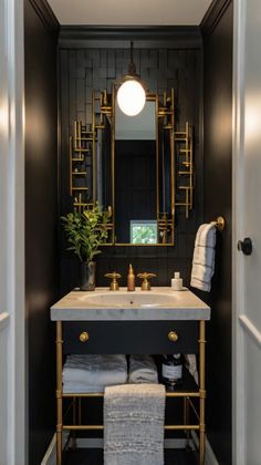 a bathroom with black walls, gold fixtures and white towels on the sink countertop