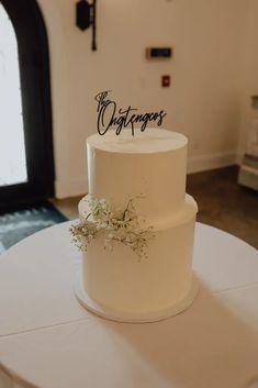 a three tiered white wedding cake with the word congratulations written on it and flowers