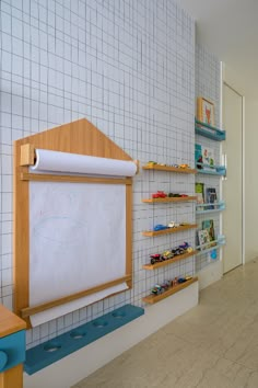 a child's playroom with shelves and toys on the wall, along with a whiteboard