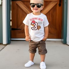 a young boy wearing sunglasses standing in front of a door with his hands on his hips