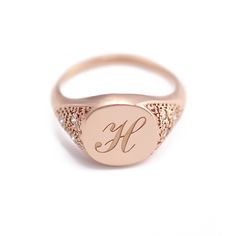 a pink gold signet ring with the letter f on it's center and diamond accents