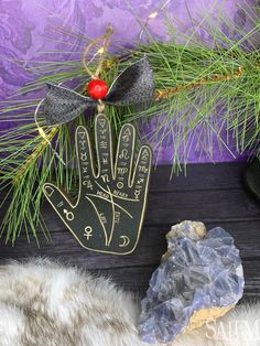 a christmas decoration with a hand on it next to a rock and pine tree branch