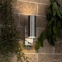 a wall mounted light on the side of a brick building next to a planter