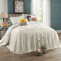 a bedroom with blue walls and white bedding has flowers on the nightstands next to it