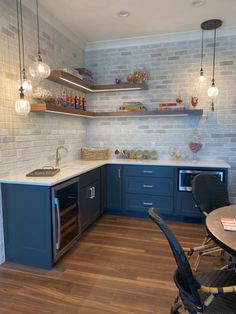 an empty kitchen with blue cabinets and wood flooring is pictured in this image, there are hanging lights above the sink