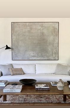 a living room filled with furniture and a large painting on the wall above it's coffee table