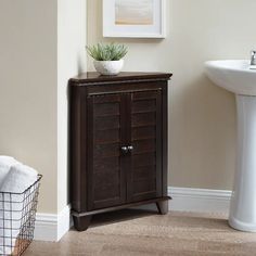 a white sink sitting next to a wooden cabinet in a bathroom under a painting on the wall