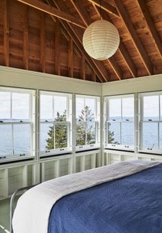 a bedroom with large windows overlooking the water