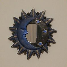 a blue sun and moon shaped mirror hanging on the wall next to a white wall